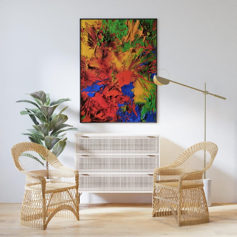 K&ouml;nnte beinhalten: Zwei Korbst&uuml;hle mit einer wei&szlig;en Kommode und einem gerahmten abstrakten Gem&auml;lde mit roter, gelber, gr&uuml;ner und blauer Farbe. Das Gem&auml;lde h&auml;ngt an einer wei&szlig;en Wand.