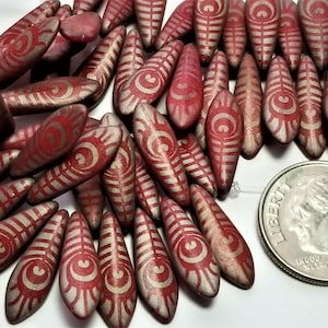 May include: A collection of red and silver glass beads with a geometric pattern. The beads are shaped like teardrops and are approximately 1 inch long.
