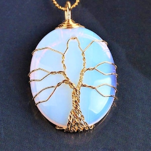 Op de afbeelding: Een met goud draad gewikkelde levensboom hanger met een witte opaal steen.