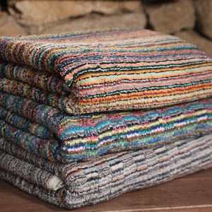 May include: A stack of colorful striped towels with a variety of patterns and colors, including blue, green, orange, and brown.