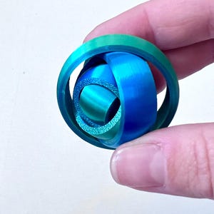 May include: A blue and green 3D printed sphere with a knot design.