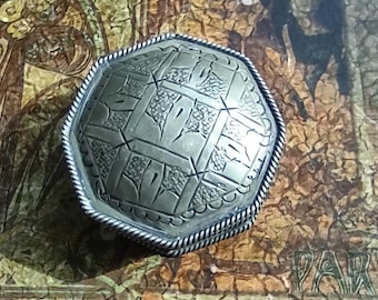 May include: A silver octagonal trinket box with an intricate geometric design. The box has a raised rim and a smooth, polished finish.