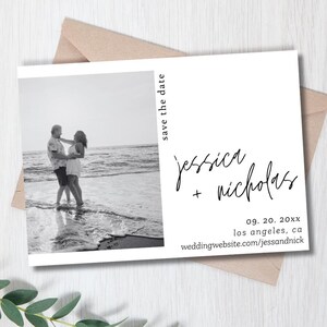 Op de afbeelding: Een zwart-witfoto van een stel op een strand met de tekst "save the date" in de rechterbovenhoek. De tekst "jessica + nicholas" is in cursief geschreven onder de foto. De datum "09. 20. 20xx" en de locatie "los angeles, ca" staan onder de namen. De website "weddingwebsite.com/jessandnick" staat onder de locatie.