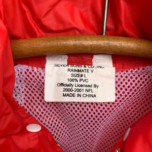 Puede incluir: Una chaqueta de lluvia roja con un forro de malla blanca. La etiqueta dice "Seven Sons & Co., Inc. Rainmate V Size# L 100% PVC Officially Licensed By 2000-2001 NFL Made in China."