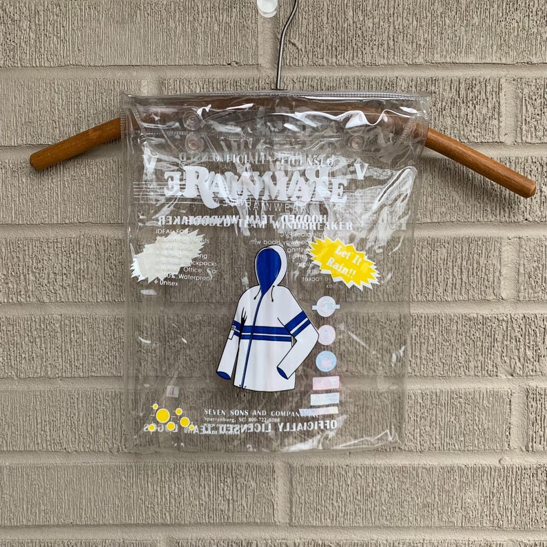 Puede incluir: Una bolsa de pl&aacute;stico transparente con cierre de cremallera, que contiene una chaqueta blanca con capucha y rayas azules. La chaqueta tiene el texto "Rainmate" impreso, junto con las palabras "Officially Licensed" y "Seven Sons and Company".