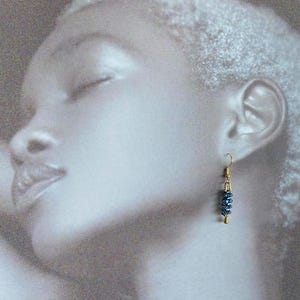 Peut inclure: Boucles d'oreilles pendantes dorées avec un groupe de perles bleu foncé.