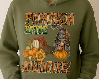 May include: Olive green hoodie with a graphic featuring a gnome, pumpkins, and sunflowers. The text "PUMPKIN SPICE ADVENTURES" is displayed in orange and green. The hoodie has a kangaroo pocket and a drawstring hood.