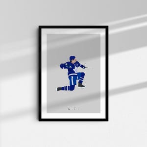 Könnte beinhalten: Eine digitale Illustration eines Hockeyspielers in einem blau-weißen Trikot mit einem Ahornblatt-Logo, der auf dem Eis Schlittschuh läuft. Der Spieler befindet sich in einer dynamischen Pose, mit dem Schläger in der Luft. Der Hintergrund ist hellgrau. Der Text "Game Frame" befindet sich am unteren Rand des Bildes.