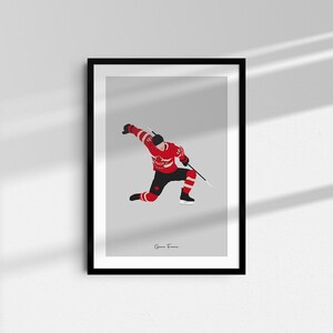 May include: A digital illustration of a hockey player wearing a red and white jersey with a Canadian flag on the front, skating and holding a hockey stick. The background is gray. The text "Game Frame" is at the bottom of the image.