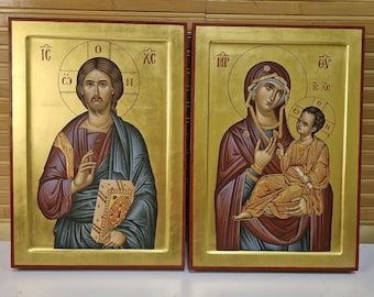 May include: Two framed religious icons with gold backgrounds and red borders. One depicts a figure with a halo, holding a book. The other shows a woman with a halo holding a child. Both icons have traditional religious imagery.