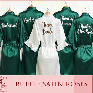 May include: Five green satin robes with white text. The robes have ruffles at the sleeves and neckline. The text on the robes reads "Bridesmaid", "Maid of Honor", "Team Bride", "Mother of the Bride", and "Maid of Honor".
