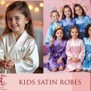 May include: A group of children wearing satin robes in various colors, including white, purple, pink, and blue. The robes have a sash tie and are decorated with a single initial on the front. The robes are perfect for a special occasion or for everyday wear.