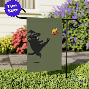 May include: A rectangular garden flag featuring a black cat wearing a witch hat and kicking a small orange jack-o'-lantern. The flag has an olive green background and is displayed on a black metal stand. A blue circular badge reads Two Sizes.