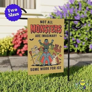 May include: A garden flag with the text "NOT ALL MONSTERS ARE IMAGINARY" and "SOME WORK FOR ICE" featuring cartoon monsters. The flag is yellow with a black metal stand, set in a grassy yard with flowers.