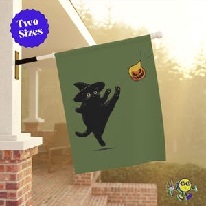 May include: A green flag featuring a black cat wearing a witch hat, reaching for a jack-o'-lantern. The flag has the text "Two Sizes" in a blue circle. The design is whimsical and Halloween-themed.