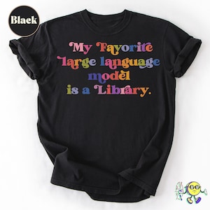 May include: A black short-sleeved t-shirt featuring the multicolored text "My Favorite large language model is a Library." in a retro-style font. The shirt has a crew neckline and a circular "Black" label in the upper left corner.