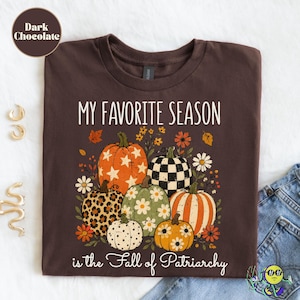May include: A dark chocolate brown t-shirt featuring the text "MY FAVORITE SEASON" and "is the Fall of Patriarchy" in white. The graphic includes six pumpkins with various patterns, including stars, leopard print, checkers, and flowers.