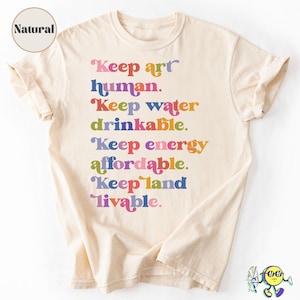 Może przedstawiać: T-shirt z krótkim rękawem w naturalnym kolorze z wielokolorowym napisem: Keep art human. Keep water drinkable. Keep energy affordable. Keep land livable. Koszulka ma okrągły dekolt i luźny krój z podwiniętymi rękawami.