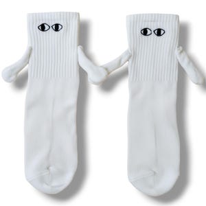 Peut inclure: Deux chaussettes blanches avec des visages de dessins animés, chacune avec des yeux noirs et des bras, se tenant la main. Les chaussettes ont un bord côtelé et un corps blanc uni, créant un design fantaisiste et ludique.