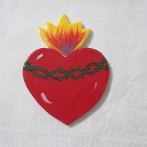 May include: A red heart with a green thorned crown and a yellow, orange, and purple flame on top.