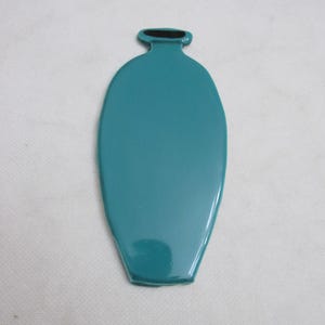 May include: A teal-colored, elongated vase-shaped object with a black opening at the top. The object has a glossy finish and a smooth surface. The vase is set against a white background.