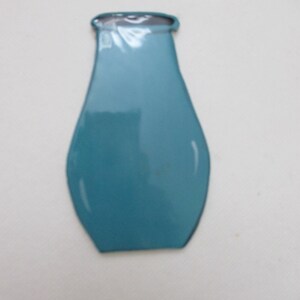 May include: A flat, two-dimensional cutout shaped like a vase with a smooth, glossy teal finish. The object features a wide, rounded body that tapers towards a narrow neck and a flat, open top rim, presenting a simple, solid-coloured silhouette.