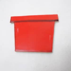May include: A bright red, trapezoidal-shaped object with a flat top edge and a slightly wider base. The item features a distinct horizontal line running across the upper section, creating a separate rectangular border along the top edge.