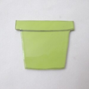 Peut inclure: Un petit objet plat en forme de pot de fleurs vert citron avec une finition lisse et brillante. L'article présente un large rebord horizontal sur le dessus et un corps effilé qui se rétrécit vers la base, offrant un design simple et uni.