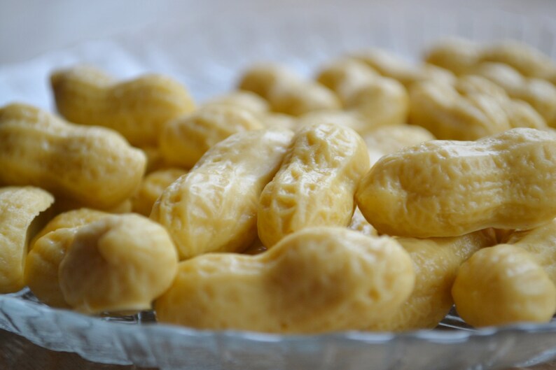 Pode incluir: Um close-up de uma tigela cheia de doces macios de cor castanho claro em forma de amendoim.