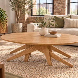 May include: A light brown wooden coffee table with an oval top and a base featuring multiple intersecting angled legs. The table surface is smooth and finished in a natural wood grain, providing a stable platform for decorative items.