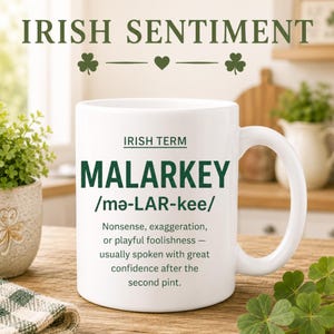 May include: White ceramic mug with the text "MALARKEY" and the definition of the Irish term. The mug also features the words "IRISH SENTIMENT" and "IRISH TERM". The mug is on a wooden surface with a small plant and a green and white checkered cloth.