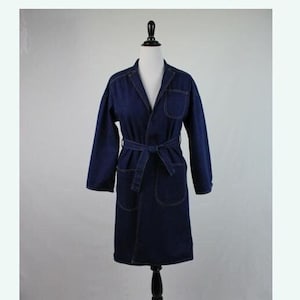 May include: A long, dark blue denim robe with a tie belt. The robe has a collar and two pockets.