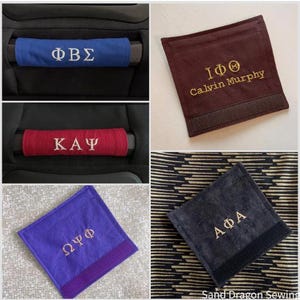Op de afbeelding: Vier verschillende stoffen armleuningshoezen met geborduurde Griekse letters en namen. De hoezen zijn in blauw, rood, paars en zwart. De hoezen zijn allemaal bevestigd met klittenband.