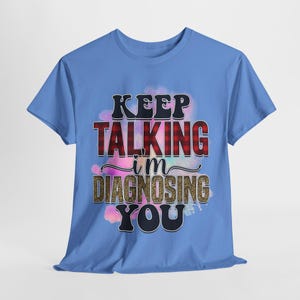 Puede incluir: Camiseta azul claro con un diseño de acuarela colorido y el texto "Keep Talking I'm Diagnosing You".