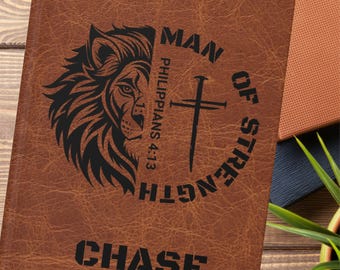 Può includere: Diario in pelle marrone con grafica di leone e testo "MAN OF STRENGTH" e "PHILIPPIANS 4:13". Il nome "CHASE" è stampato in basso. Il diario è chiuso e sembra nuovo.