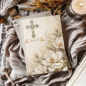 May include: A hardback book with a cream-coloured cover featuring a decorative cross, the text "Chapter 70" on a banner, and a floral illustration of white magnolia blossoms. A gold-trimmed label at the bottom displays the name "Norma".