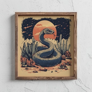 May include: A framed art print featuring a stylized illustration of a coiled snake in a desert landscape. The snake is blue and gray, with its tongue extended. The background includes a setting sun, cacti, and rocks.