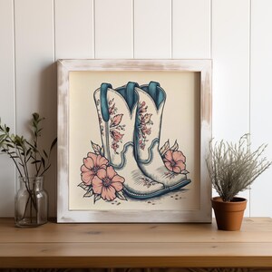 Puede incluir: Un par de botas vaqueras blancas con bordados florales, sobre un fondo crema. Las botas tienen detalles azules y están rodeadas de flores rosas.