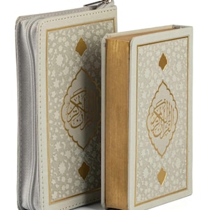 May include: Two books with ornate gold lettering and designs. The books have a light gray cover with a floral pattern and gold accents. One book is zippered, and the other has gold-gilded edges.