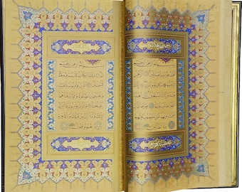 May include: An open book with intricate gold and blue designs on the cover and pages. The text on the pages is in Arabic script.