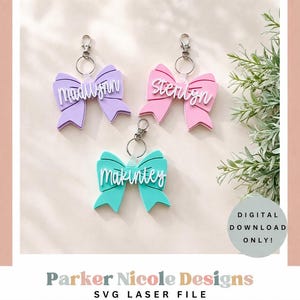 Può includere: Tre portachiavi a forma di fiocco in viola, rosa e turchese, ciascuno con un nome in corsivo bianco. I portachiavi hanno finiture color argento e sono esposti con del verde. È visibile anche il testo "SOLO DOWNLOAD DIGITALE!"