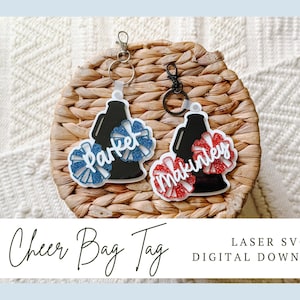 May include: Two custom acrylic bag tags featuring a black megaphone shape and glittery pom-poms. One tag has blue pom-poms with the name Parker in white script, and the other has red pom-poms with the name Makinley in white script, each with a metal keyring.