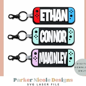 Puede incluir: Tres llaveros rectangulares con bases negras y letras blancas que dicen ETHAN, CONNOR y MAKINLEY. Cada uno presenta controladores laterales coloridos en rojo, azul, verde azulado y rosa claro, con un anillo y un cierre de metal negro.