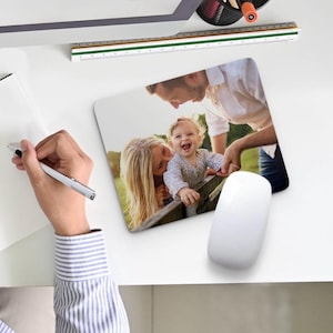 May include: A personalized mousepad featuring a photo of a family of three. The photo shows a man, a woman, and a young child smiling and looking at the camera. The mousepad is a great way to add a personal touch to your workspace.