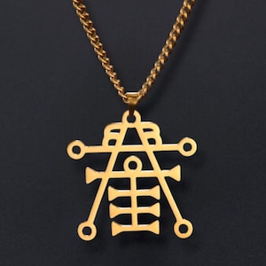 May include: Gold-colored pendant necklace featuring a geometric design with a chain. The pendant has a complex, symmetrical shape with circular and linear elements. The necklace is displayed against a dark background.