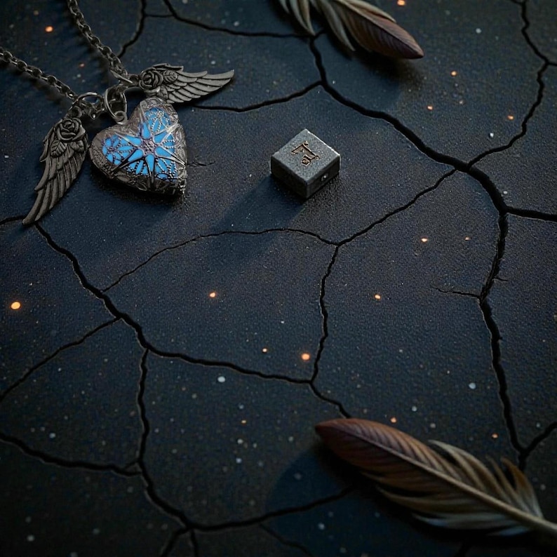 Pu&ograve; includere: Una collana con ciondolo a forma di cuore argentato con dettagli blu e ali d'angelo. Accanto c'&egrave; una piccola scatola quadrata di metallo con dettagli incisi. Sono presenti anche due piume marroni, il tutto su una superficie scura e strutturata.