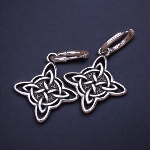 Peut inclure: Une paire de boucles d'oreilles en argent avec un nœud celtique. Chaque boucle d'oreille présente un motif de nœud détaillé avec une fermeture en anneau.
