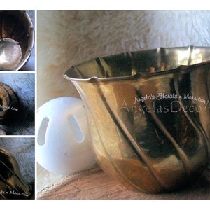 May include: A gold-coloured brass planter with a fluted rim and a swirling design. The planter is next to a white plastic ball with two holes. The image also includes detail shots of the planter. Text on the image reads: Angela's Florals n More, Angelas Deco Accents.