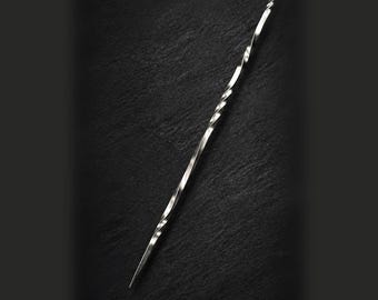 May include: A long, slender, silver-colored metal skewer featuring a distinct twisted, spiral design along its central shaft. The object has a sharp, pointed tip at one end and a flat, angled cut at the opposite end, with a polished, reflective finish.