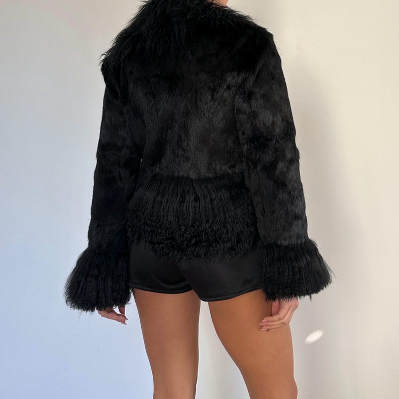 Peut inclure: Veste en fausse fourrure noire avec un aspect textur&eacute; et hirsute. La veste pr&eacute;sente un col montant, des manches longues avec des poignets &eacute;vas&eacute;s et un ourlet &agrave; franges. Le v&ecirc;tement est con&ccedil;u pour &ecirc;tre port&eacute; en ext&eacute;rieur.